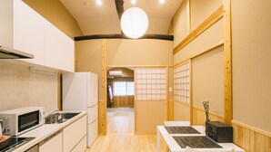 A modern kitchen with white appliances, a dining area with a table and chairs, and a traditional Japanese sliding door. - Miro Saiinnishi Imadacho Tei (Kyoto)