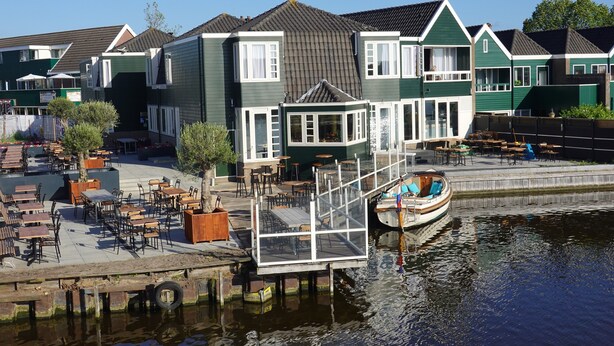A waterfront property with a dock, outdoor seating, and a boat. - Boutique Hotel Zaan (Zaandijk)