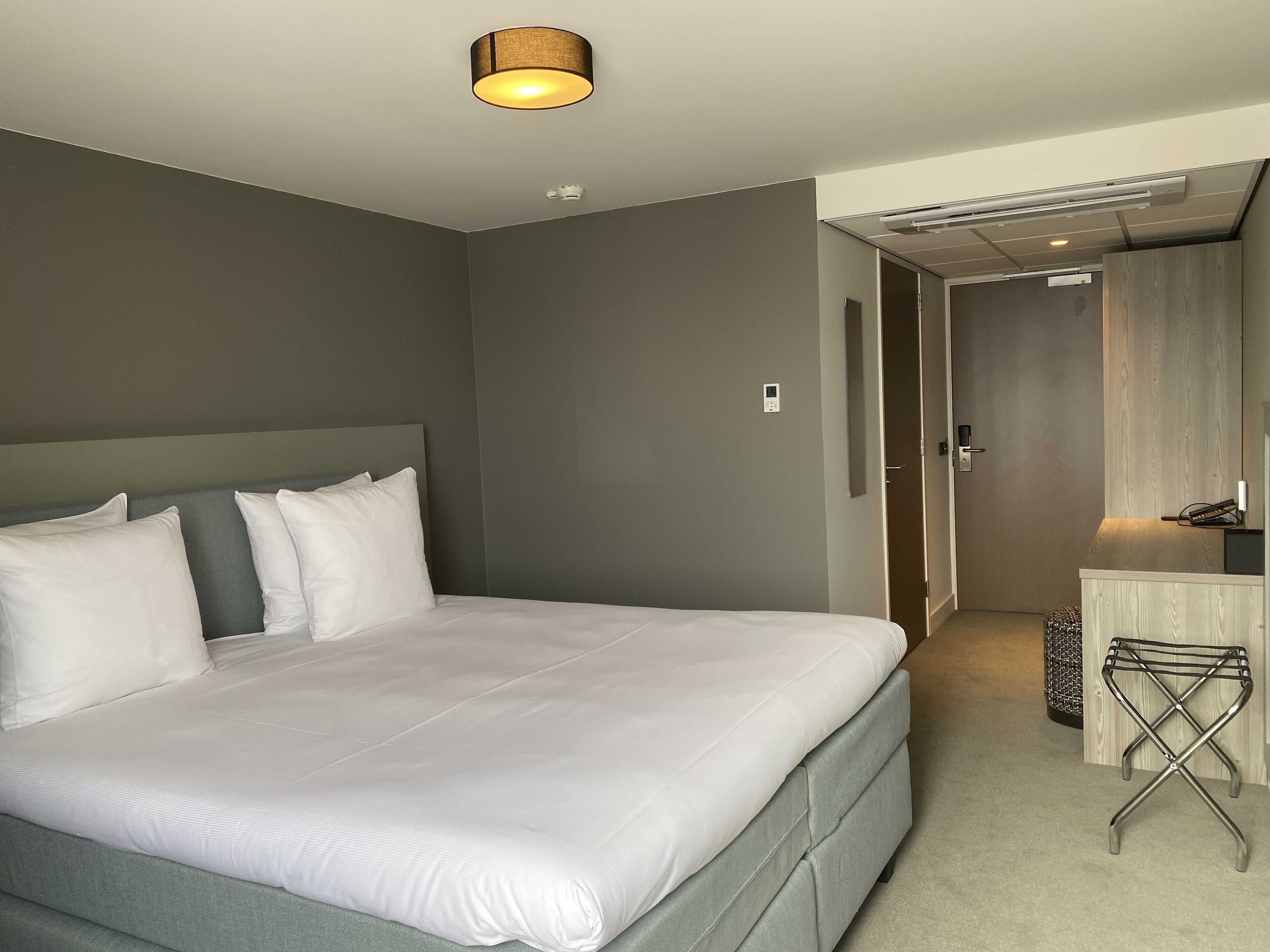 Una habitación de hotel moderna con una cama grande, una mesita de noche y un pequeño rincón de descanso.