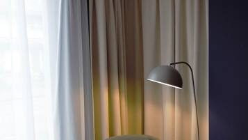 Ein Eckzimmer mit Sessel, Stehlampe und Vorhängen.