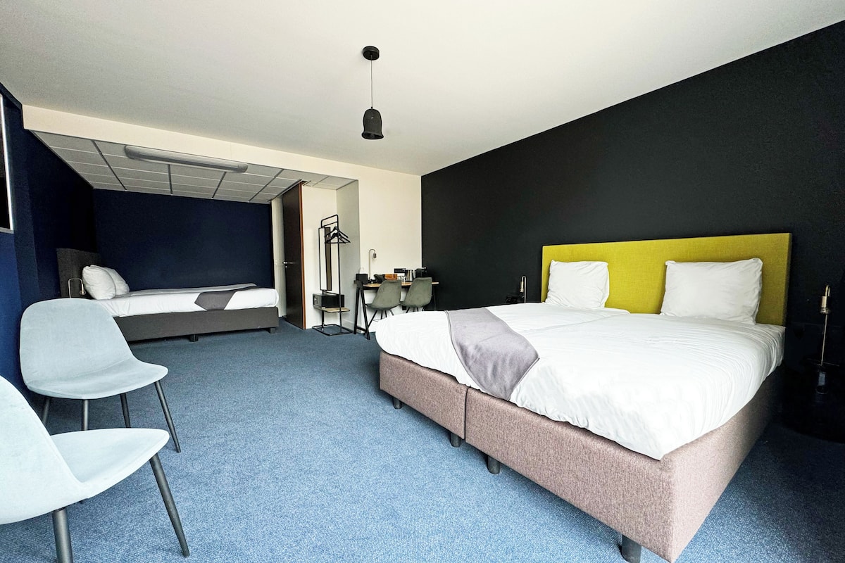 Une chambre d’hôtel moderne, dotée d’un grand lit, d’un bureau et d’une chaise.