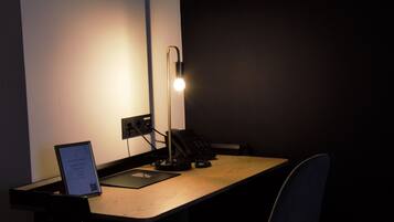 A desk with a lamp, a phone, and a sign on a stand.
