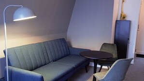A room with a sofa, a small round table, and a chair. - Boutique Hotel Zaan (Zaandijk)
