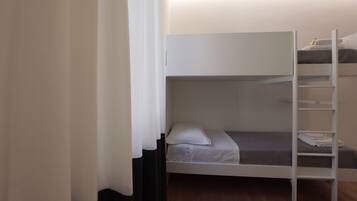 A bunk bed with a ladder, a white curtain, and a small shelf with towels.