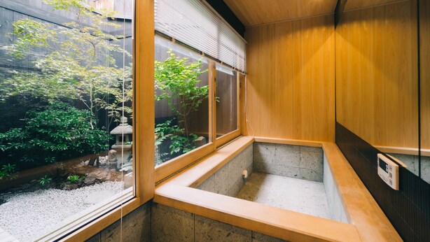 Une pièce de style japonais traditionnel, avec un sol recouvert de tatamis, un paravent en papier de riz (shoji) et une vue sur un jardin.