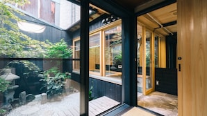 Un intérieur moderne avec de grandes portes vitrées donnant sur une terrasse en bois et un petit jardin.