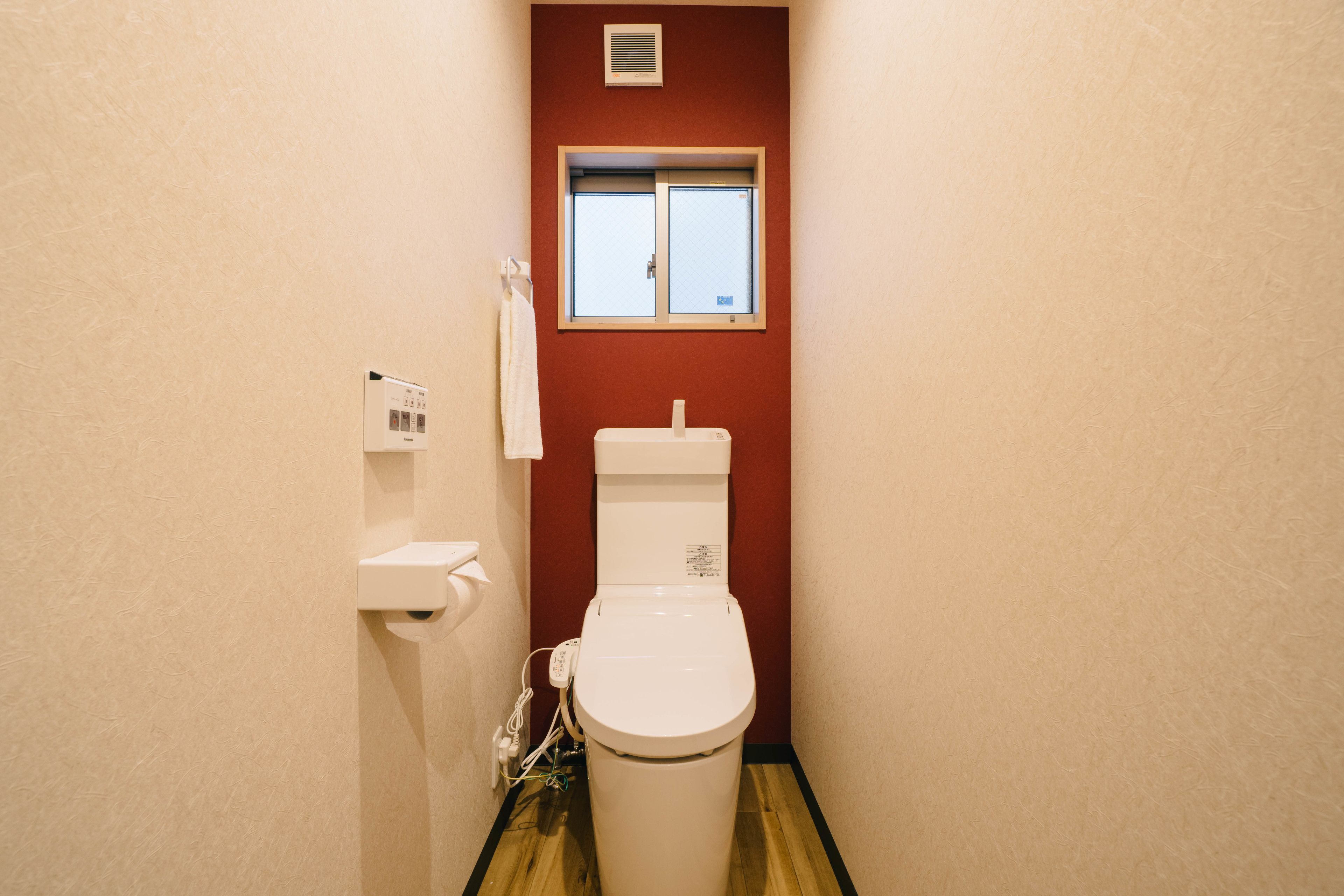 A small bathroom with a toilet, a window, and a towel rack.