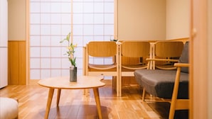 A room with a wooden floor, a round table with a potted plant, and three wooden chairs. - Miro Sanjo Saiin Tei (Kyoto)