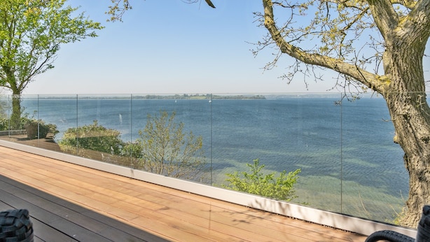 A wooden deck with a view of a lake and distant land.