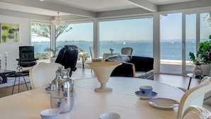 A dining area with a table set for two, overlooking a scenic view of the sea.