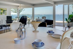 A dining area with a table set for two, overlooking a scenic view of the sea. - Fjordhuset (Broager)