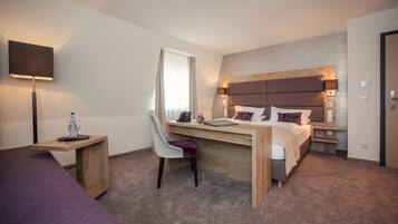 Una habitación de hotel con cama, escritorio, silla, lámpara y televisor.