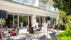 Ein möblierter Patio mit Korbmöbeln, Tischen und Liegestühlen.