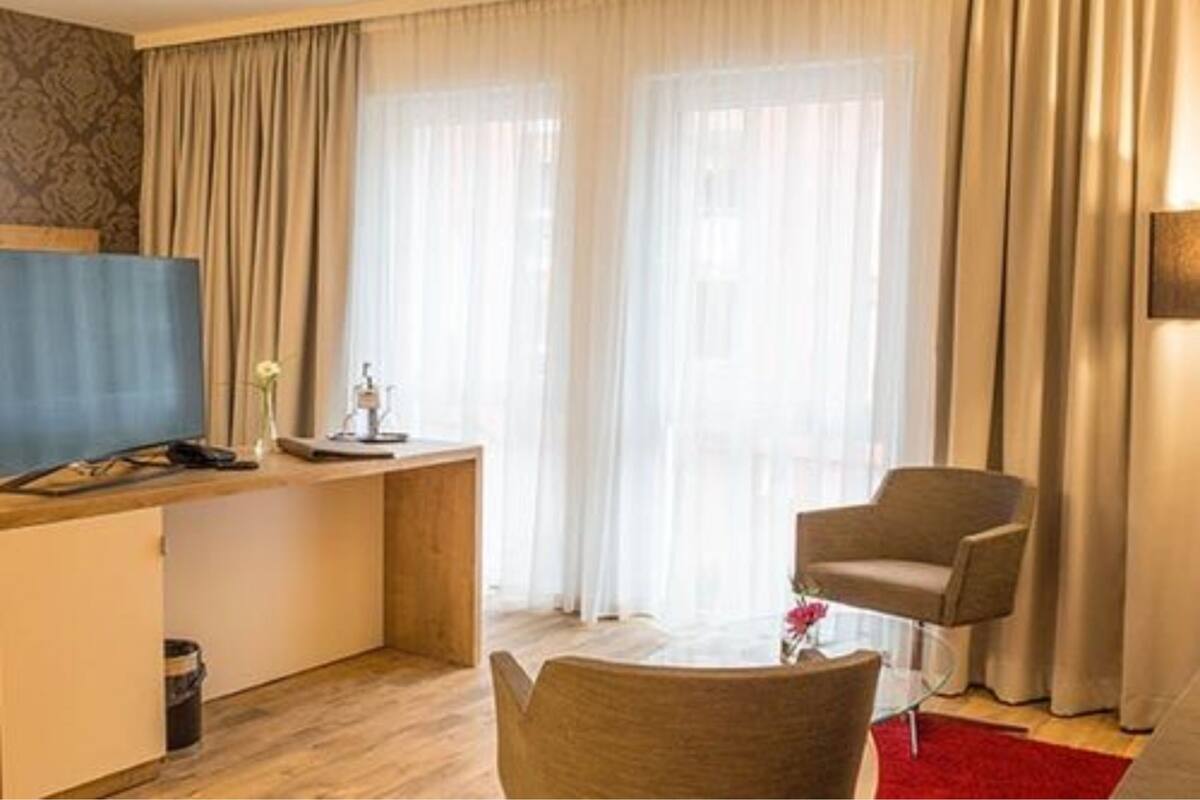 Une chambre d’hôtel avec un bureau en bois, une télévision, une chaise et un tapis rouge.