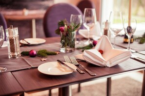 Una mesa de comedor preparada con platos, cubiertos, vasos y un centro de mesa decorativo.