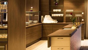 Eine moderne Küche mit Holzschränken, einer zentralen Kochinsel mit Spüle und glasfrontigen Regalen zur Präsentation von Küchenutensilien.