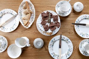 A wooden table with floral-patterned plates, a knife, and a cup.
