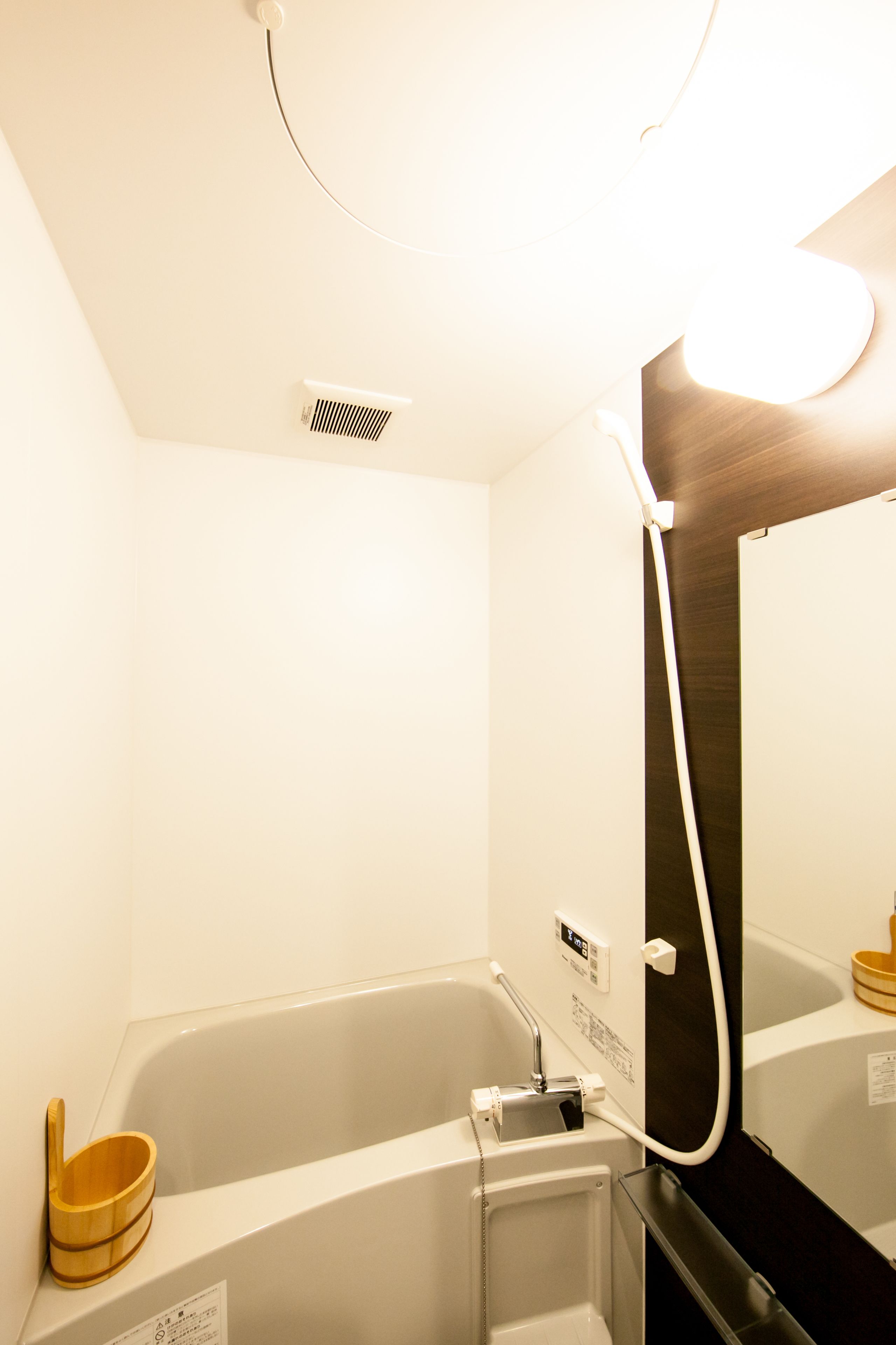 A modern bathroom with a bathtub, a wooden bath mat, and a mirror.