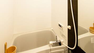 A modern bathroom with a bathtub, a wooden bath mat, and a mirror.