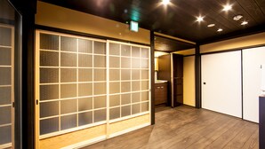 Een hotelkamer met schuifdeuren, houten vloeren en een plafond met inbouwspots.