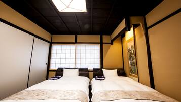 A traditional Japanese-style room with two beds, a tatami mat floor, sliding doors, and a shoji screen window.