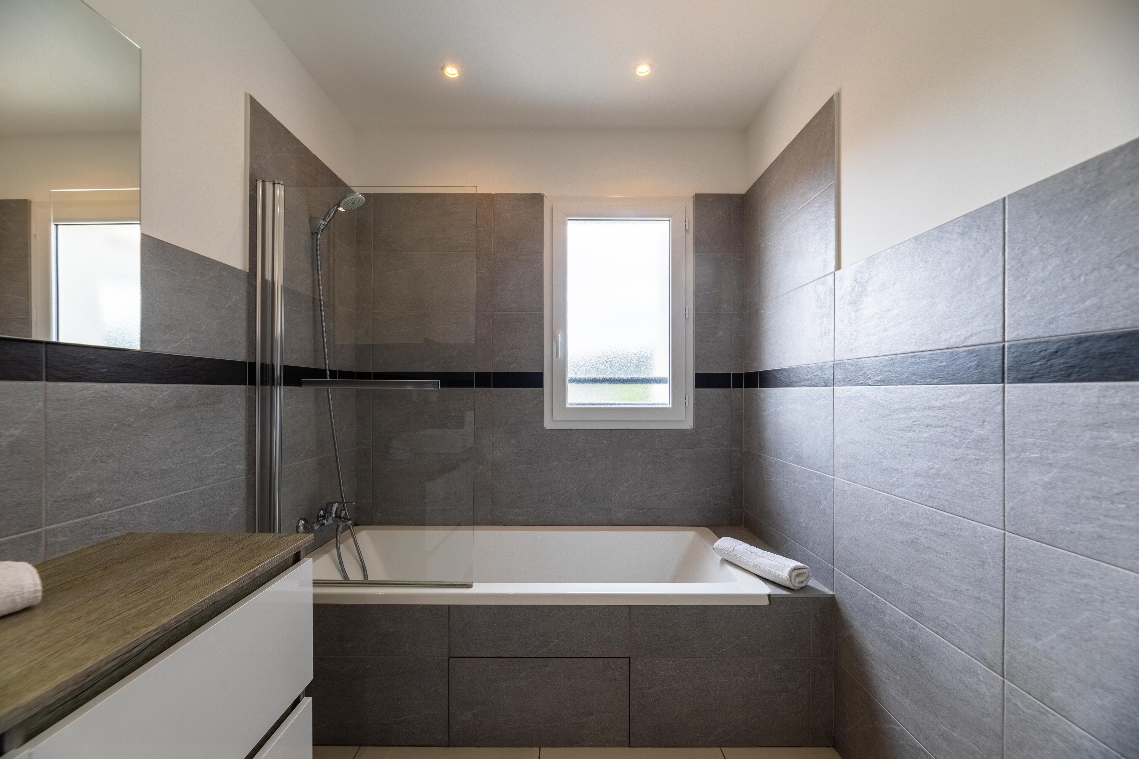 Un baño moderno con bañera, ducha y ventana.