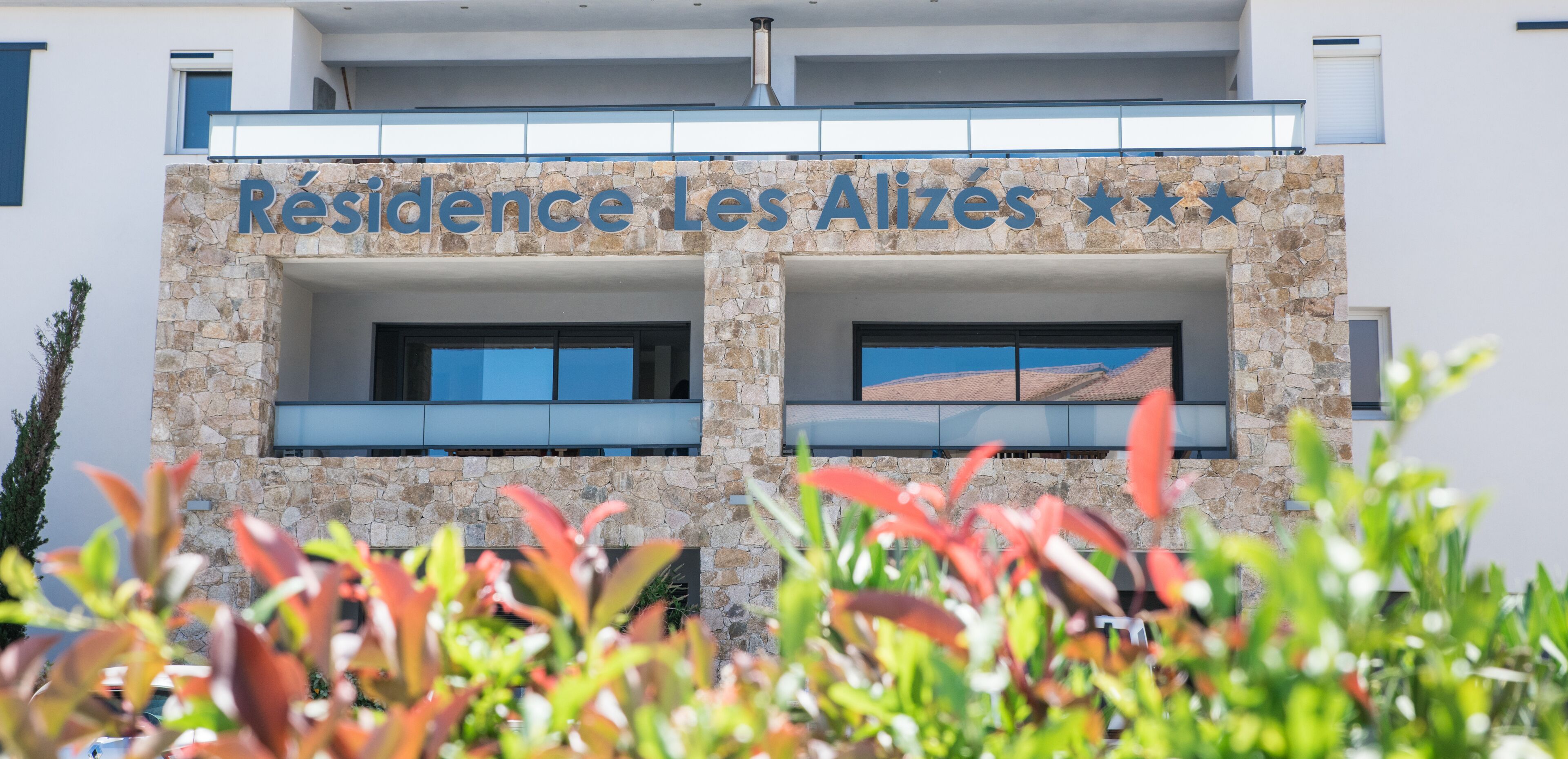 A building with a stone facade and a sign that reads "Résidence Les Alizes".