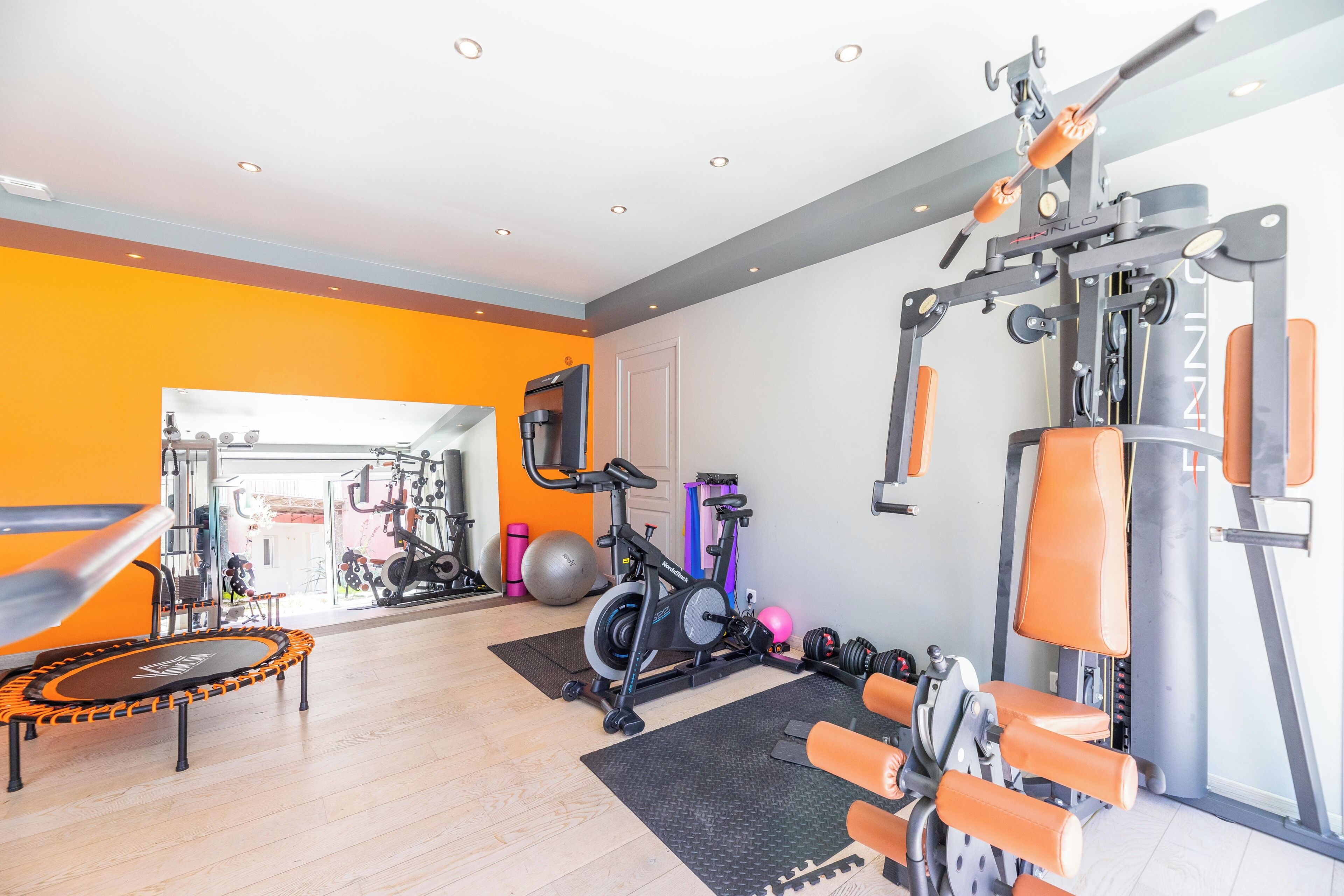 Une salle de sport équipée de matériel d’exercice, d’un trampoline et d’une grande fenêtre.