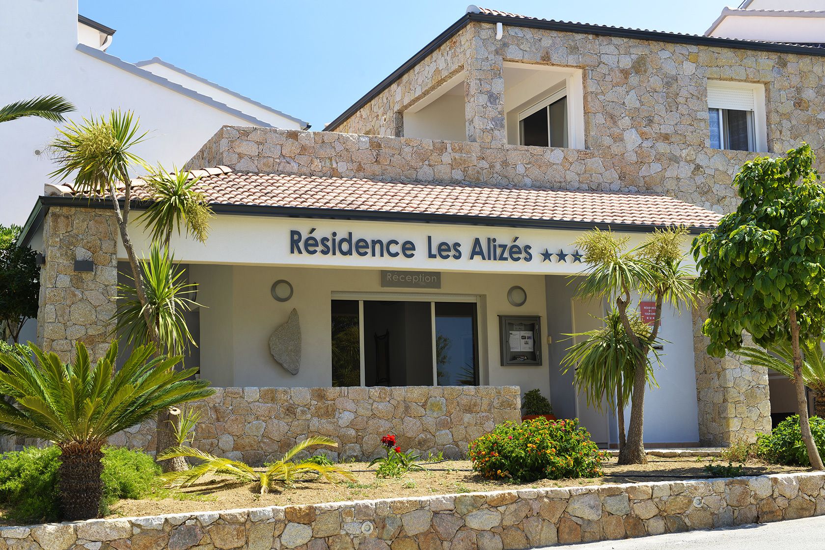 Un bâtiment en pierre sur lequel on peut lire l’inscription : « Résidence Les Alizés ».