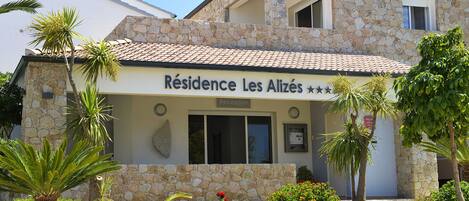 A stone building with a sign reading "Résidence Les Alizés".