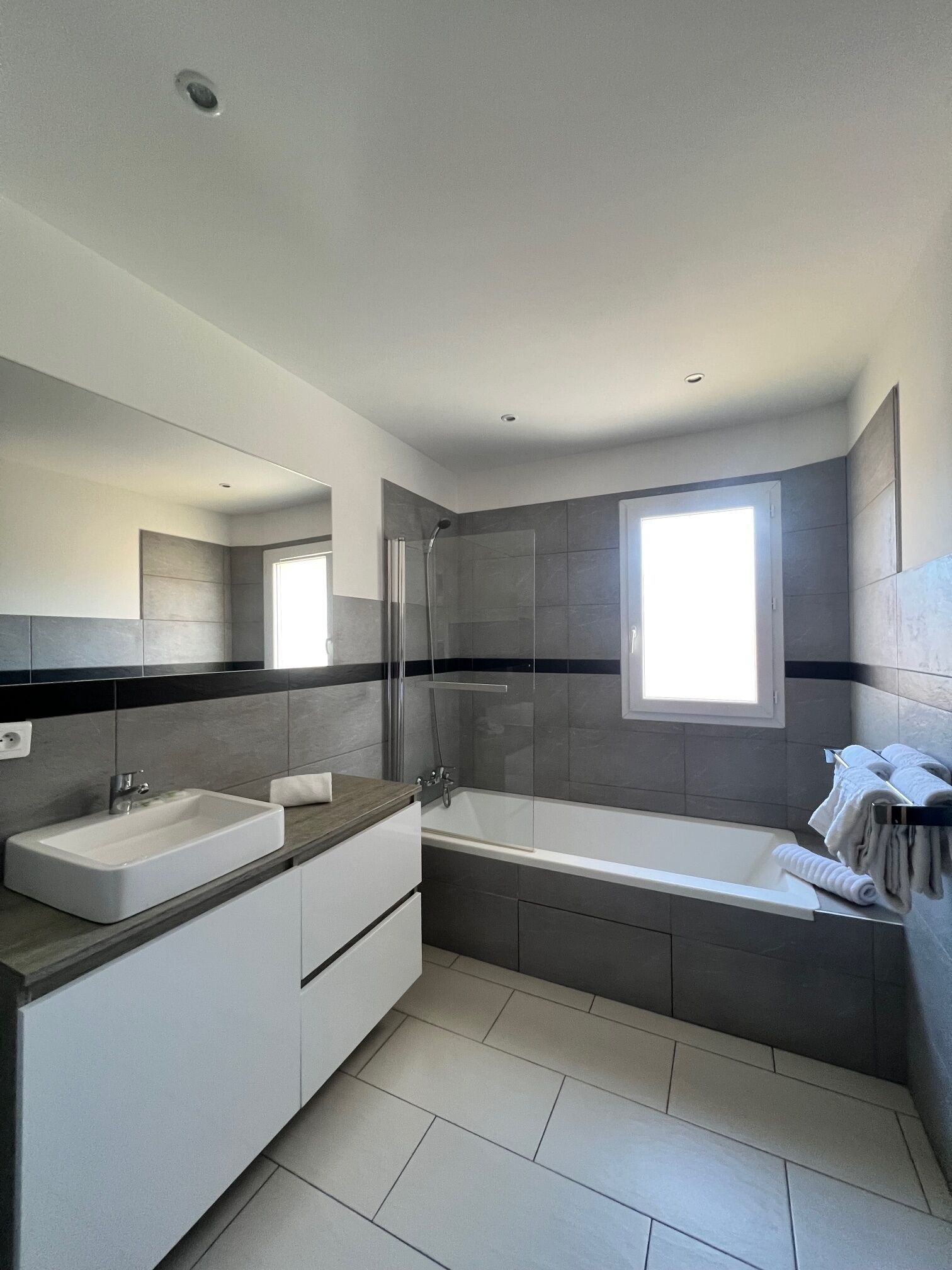 A modern bathroom with a bathtub, a shower, and a sink.
