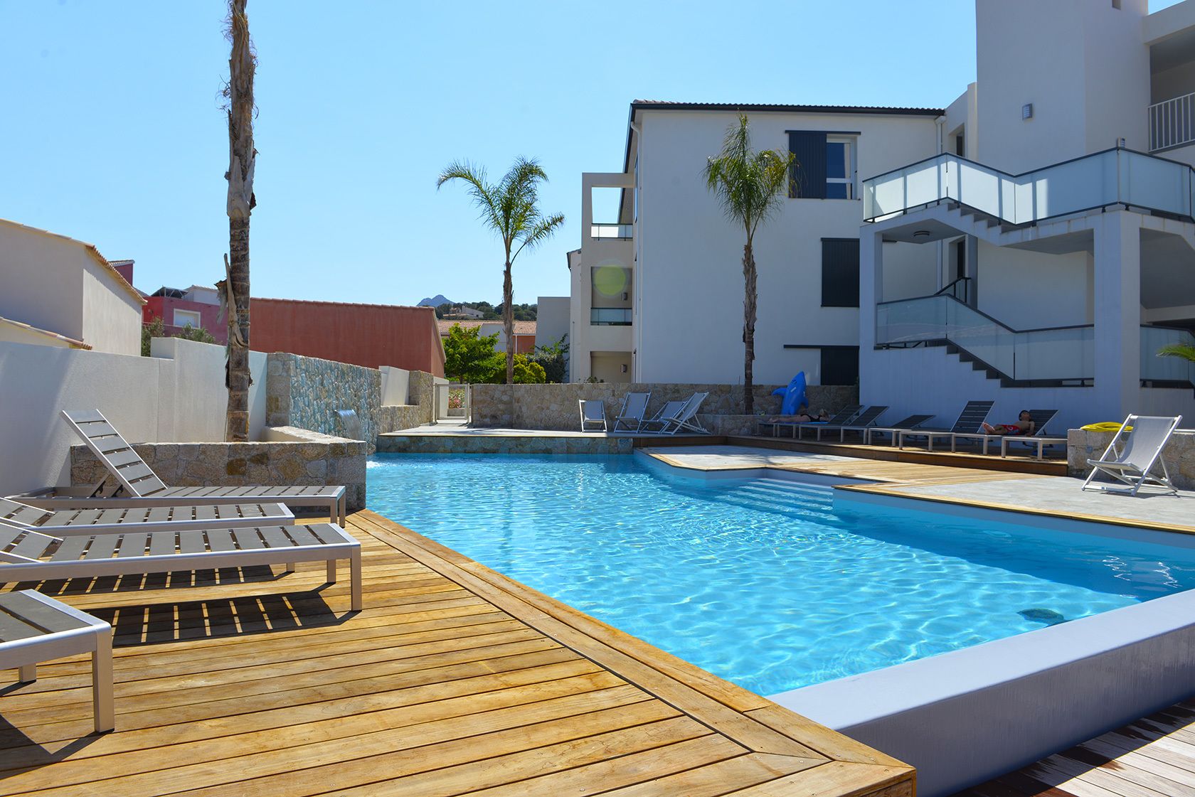 Ein Schwimmbecken mit Liegestühlen und einer Holzterrasse.