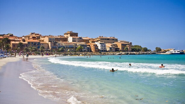 A coastal town with a beach, clear waters, and buildings in the background. - Les Alizés Résidence & Spa  (Monticello)