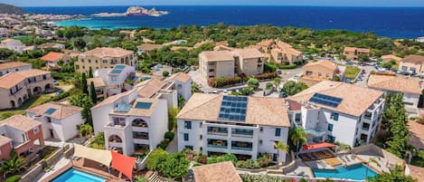 Zona residencial costera con varios edificios, una piscina y vista al mar.