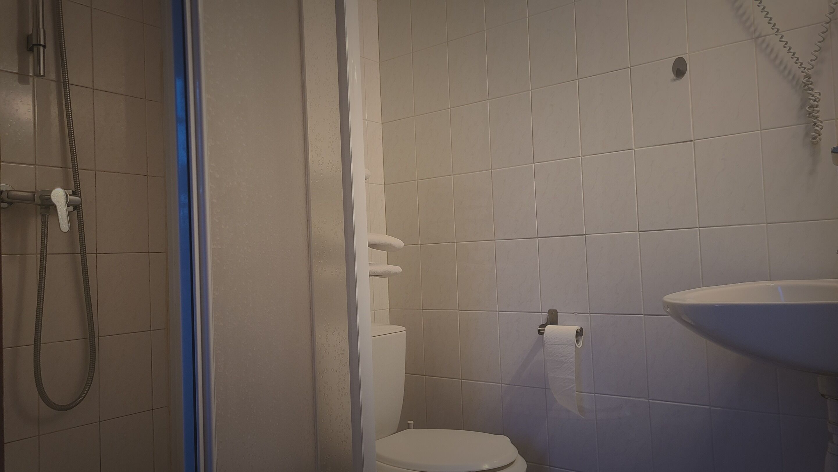 Un baño pequeño con inodoro, ducha y lavamanos.