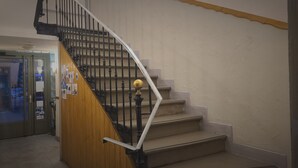 A staircase with a wooden handrail and black balusters, leading to a landing with a door. - Hôtel Restaurant Glaizette (L'Argentiere-la-Bessee)