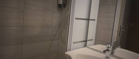 A bathroom with a shower, a sink, and a mirror.