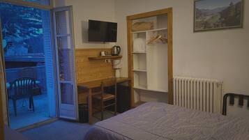 Een slaapkamer met een bed, een bureau, een stoel, een televisie, een radiator en een kledingkast.