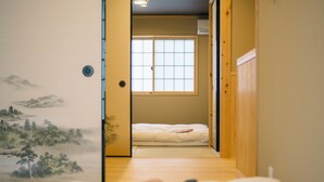 A traditional Japanese room with tatami flooring, a futon bed, a shoji screen door, and a mural on the wall. - Miro Shijo Saiin Tei (Kyoto)