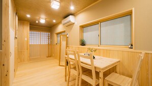 A wooden dining area with a table and chairs, a window with a view, and an air conditioning unit on the ceiling. - Miro Shijo Saiin Tei (Kyoto)