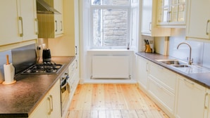 A kitchen with white cabinets, a window with a view, a stove, and a sink.