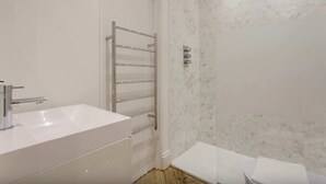 A modern bathroom with a white sink, a chrome towel rack, and a white toilet. - Elegant 1 Bedroom Apartment in South Kensington (London)