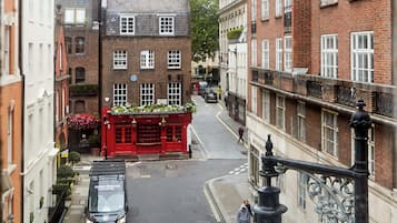 Una calle estrecha flanqueada por edificios, un edificio rojo con un letrero y un coche estacionado.