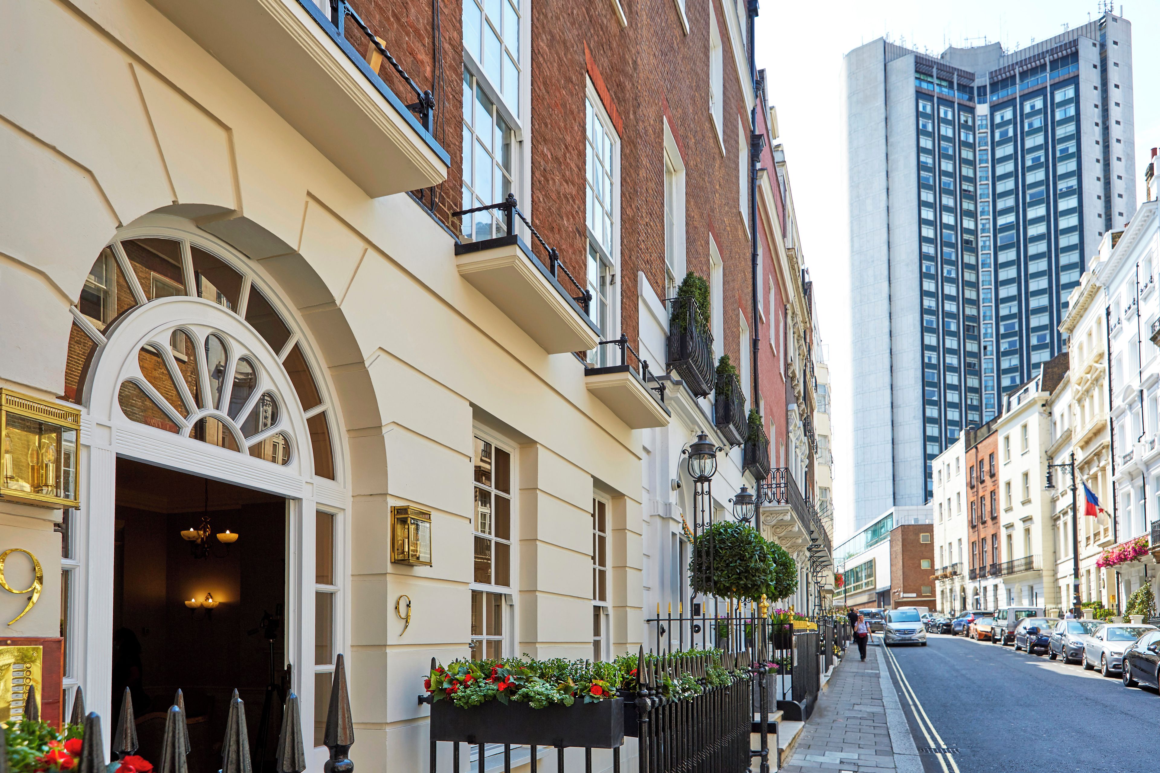 A row of classic brick buildings with a modern glass skyscraper in the background.