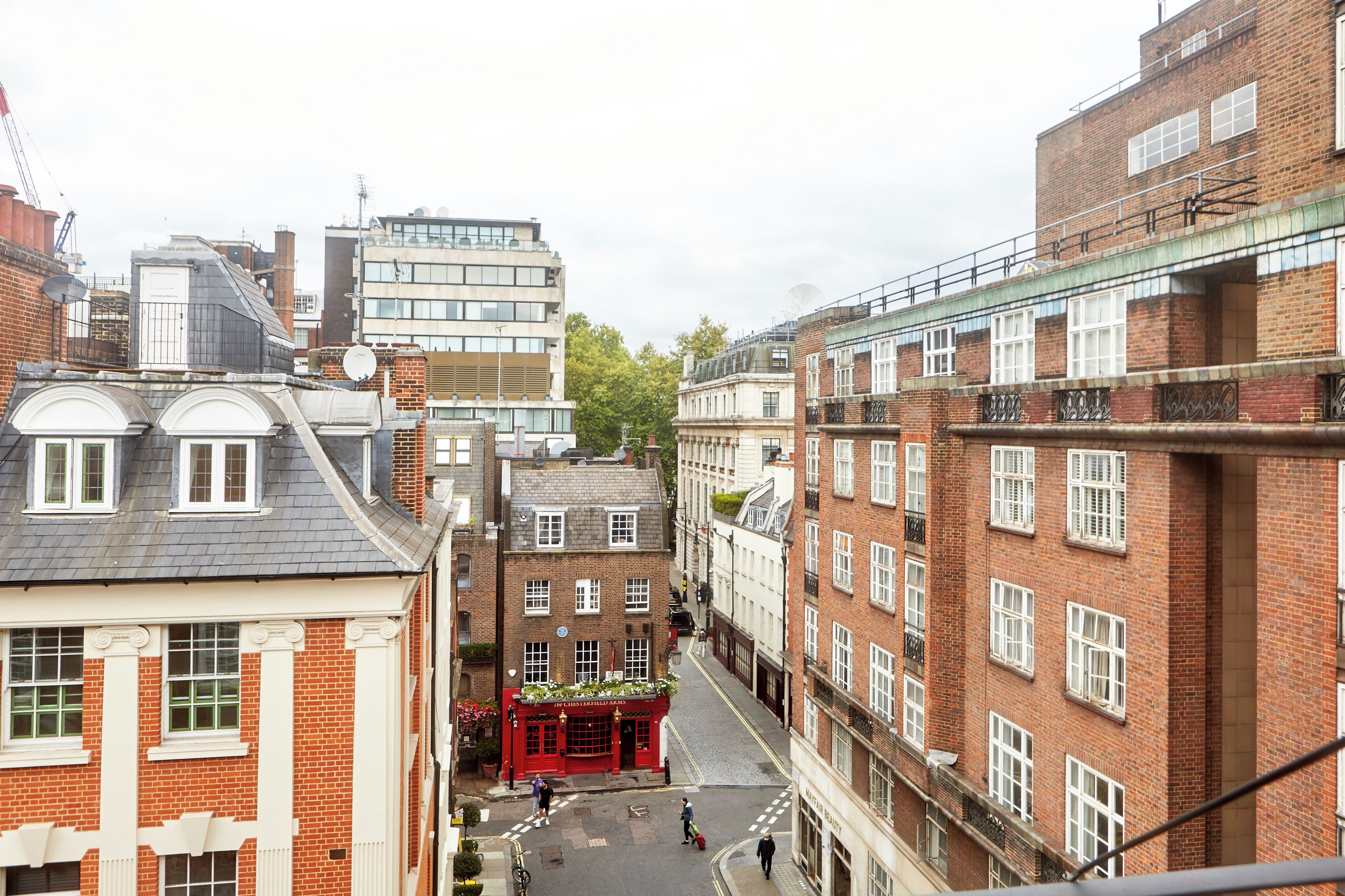 Una calle estrecha bordeada por edificios históricos, con un pub rojo y un edificio moderno al fondo.