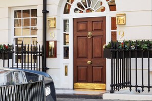 A traditional building with a prominent wooden door, a black car parked in front, and a number '9' displayed on the wall. - 9 Hertford Street Mayfair (London)