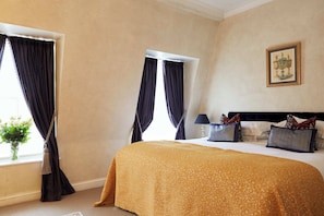 A hotel room with a large bed, two windows with dark curtains, a bedside table with a lamp, and a framed picture on the wall. - 9 Hertford Street Mayfair (London)