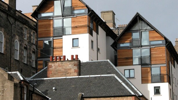 A modern multi-story building with a mix of brick and wooden facade, large windows, and a sloped roof. - Bright, Modern Apartment - Royal Mile (Edinburgh)