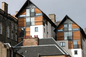 Un edificio moderno de varios pisos con una fachada combinada de ladrillo y madera, ventanas amplias y un techo inclinado.