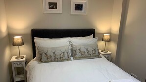 A neatly made bed with white linens and decorative pillows, flanked by two bedside lamps with lampshades. - Bright, Modern Apartment - Royal Mile (Edinburgh)